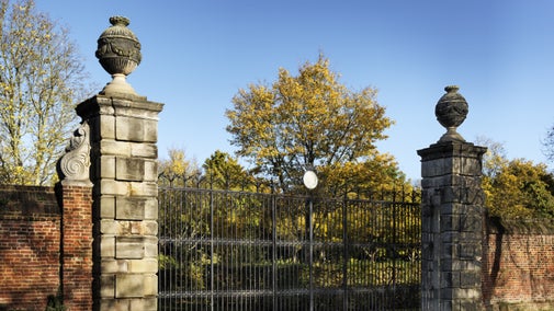 The large wrought-iron south gate at Ham House, London set in the red-brick wall of the grounds and flanked by pillars